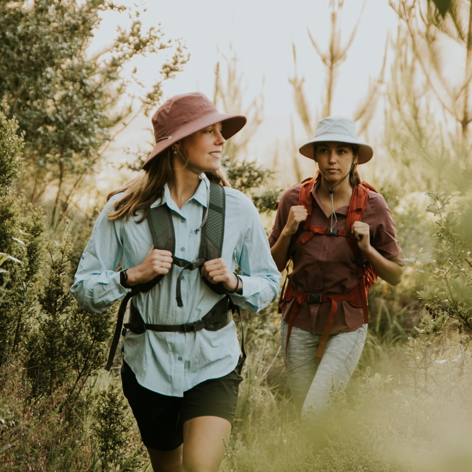 Two ladies walking in the forest with First Ascent hiking apparel and gear