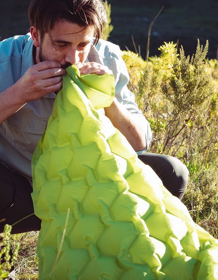 Man blowing up a First Ascent hiking mattress